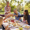 Two families making a toast at picnic at a table in a park