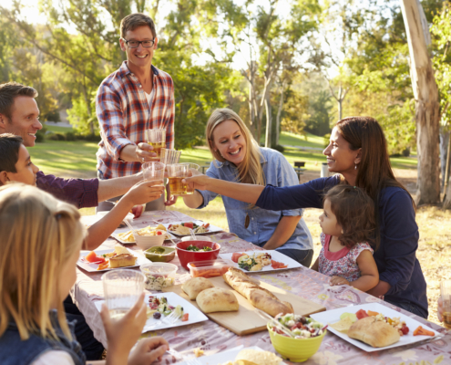 Two families making a toast at picnic at a table in a park